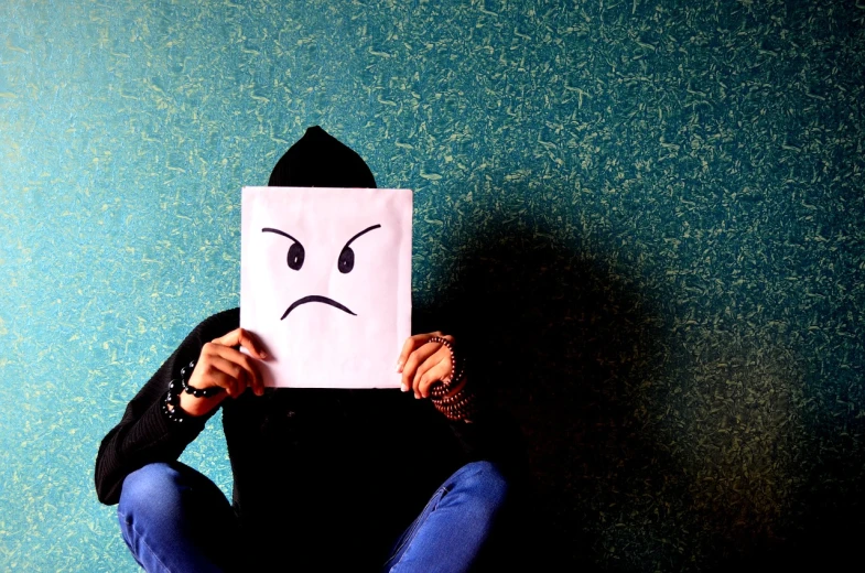 a person holding a paper with a sad face drawn on it, shutterstock, angry look, background image, bad attitude, no face