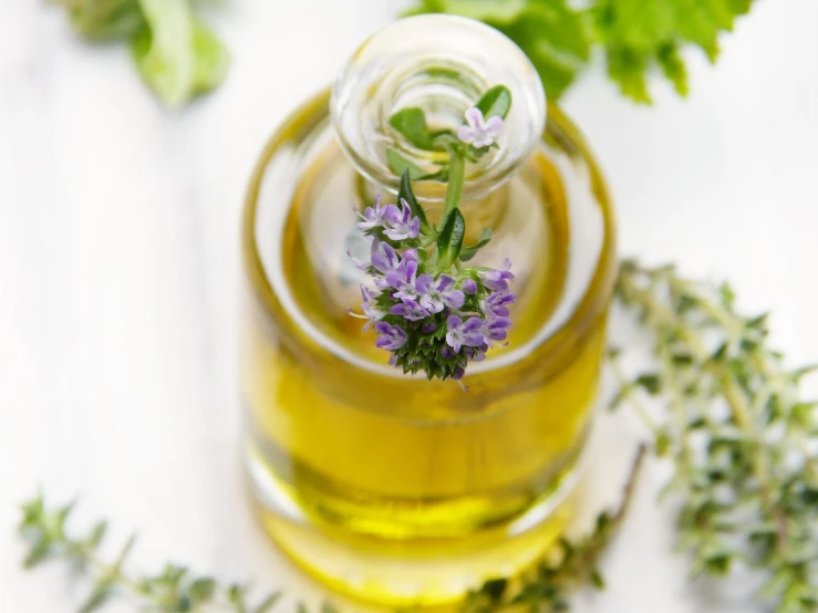 a close up of a bottle of oil with flowers, by Anna Haifisch, pexels, verbena, avatar image, flowers growing out of its head, herbs