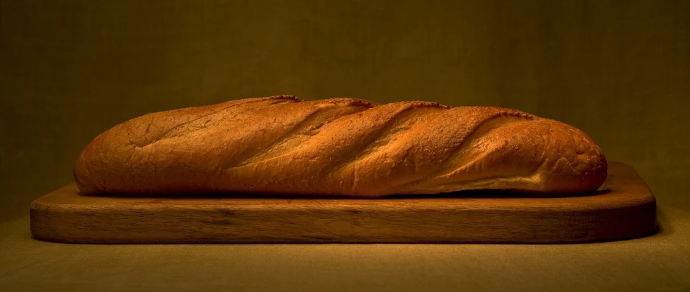 a loaf of bread sitting on top of a wooden cutting board, by Jan Rustem, unsplash, hyperrealism, baking french baguette, dimly lit, tall and slender, taken in the mid 2000s