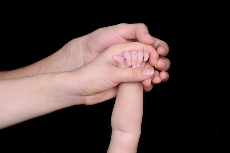 a close up of a person holding a baby's hand, a stock photo, by Juan O'Gorman, shutterstock, symbolism, on black background, polish, different sizes, vertical orientation