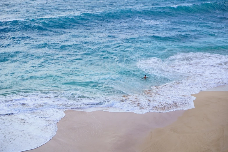 a person riding a surfboard on top of a sandy beach, by Richard Carline, pexels, minimalism, waikiki beach, bird view, azure waves of water, washed up