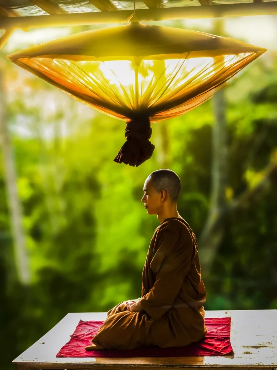 a man sitting in a meditation position under an umbrella, a picture, shutterstock, monk clothes, very beautiful photo, hanging, thawan duchanee