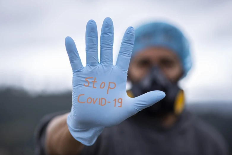 a close up of a person wearing gloves and a gas mask, a stock photo, shutterstock, graffiti, poster of corona virus, stop sign, covid-19 as a human, ship