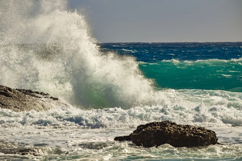 a man riding a wave on top of a surfboard, by Mathias Kollros, pexels, waves crashing at rocks, cyprus, glistening seafoam, today\'s featured photograph 4k