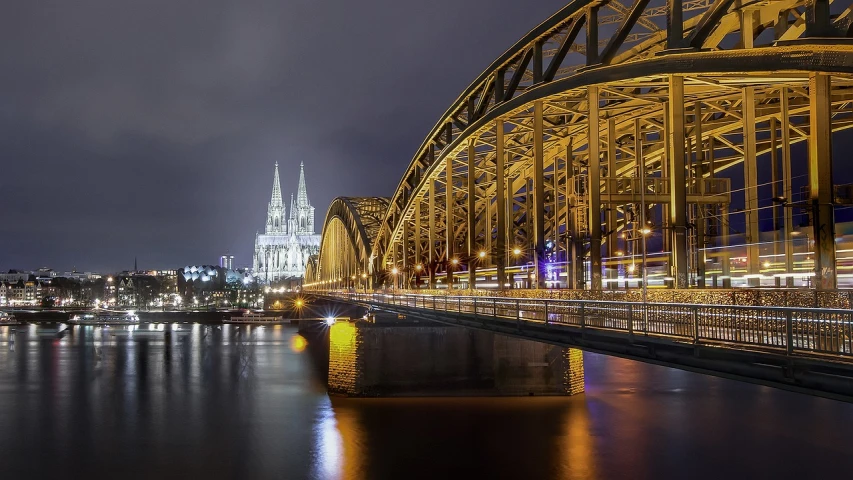 a bridge over a body of water at night, a picture, by Oskar Lüthy, pixabay contest winner, cathedrals, germany. wide shot, blonde, grey