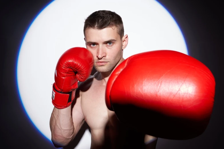 a shirtless man wearing red boxing gloves, a stock photo, professional closeup photo, is looking at the camera, male with halo, man standing in defensive pose