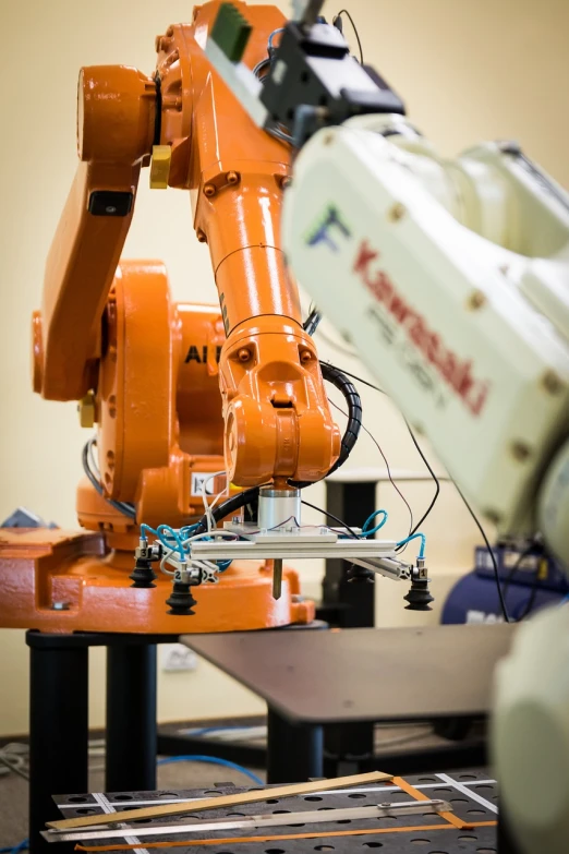 a robot that is sitting on a table, by Jakob Gauermann, shutterstock, machinery, close-up shot taken from behind, tilt and orange, handling laboratory equipment