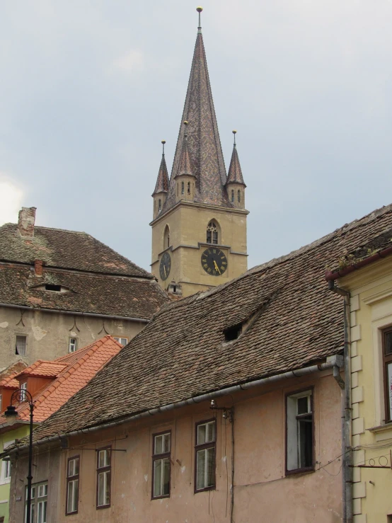 a clock that is on the side of a building, inspired by Ernő Tibor, romanesque, sharp roofs, view from across the street, lead - covered spire, very old
