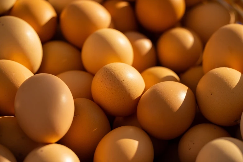 a basket full of eggs sitting on top of a table, a stock photo, shutterstock, strong eggshell texture, high angle close up shot, warm sunshine, egypt