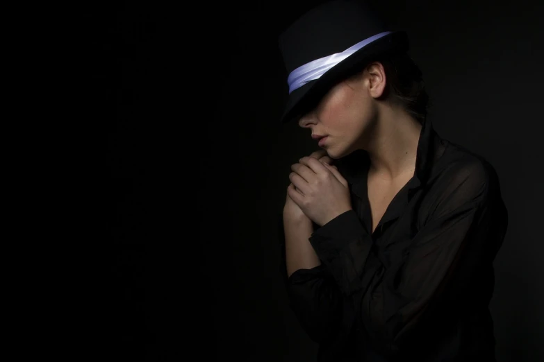 a woman in a black shirt and a hat, by Thomas Häfner, flickr, minimalism, glowing with colored light, young female in black tuxedo, praying, blues