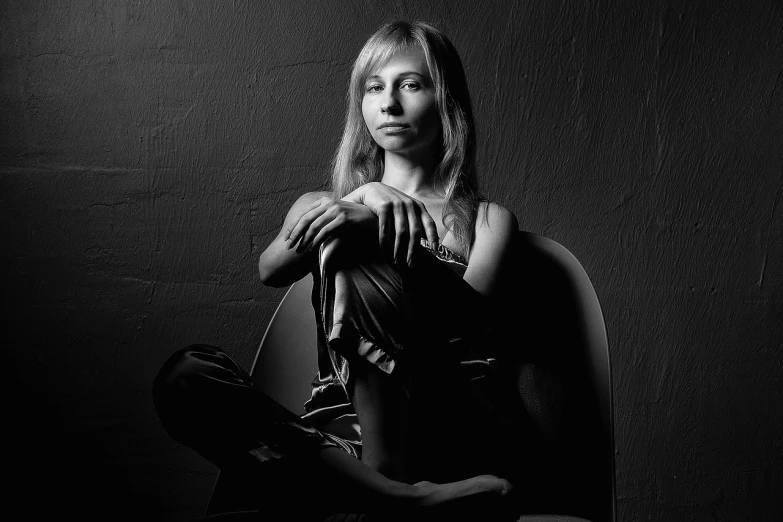 a black and white photo of a woman sitting on a chair, a portrait, art photography, olya bossak, shot at dark with studio lights, portrait of a blonde woman, nft portrait