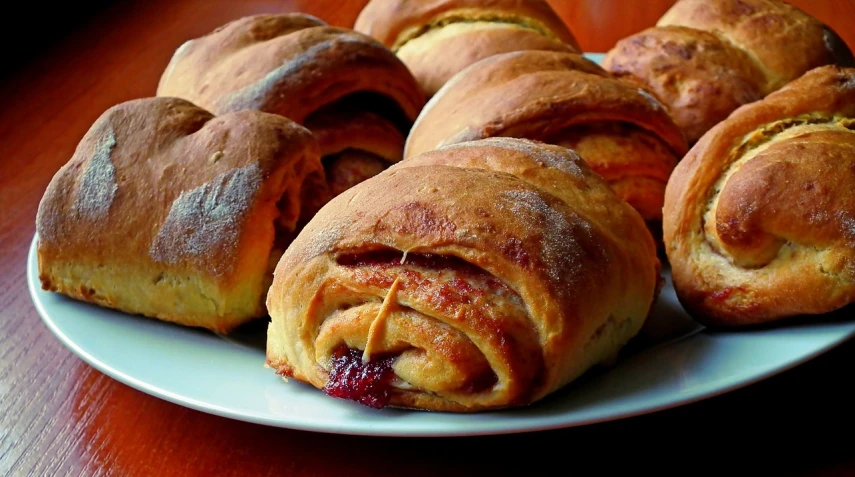 a white plate topped with pastries on top of a wooden table, inspired by Károly Patkó, pixabay, blanket, reds, gradins, twisting