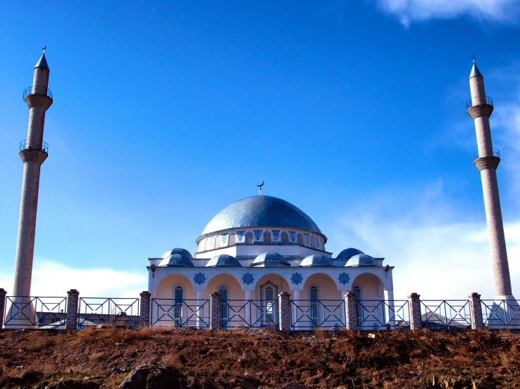 a large white and blue building sitting on top of a hill, hurufiyya, rounded roof, pray, otjize, metal