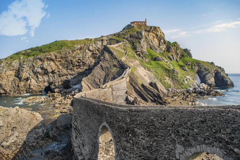 a stone bridge over a body of water, a picture, by Carlo Martini, pexels, renaissance, cinq terre, totalitarian prison island, iso 1 0 0 wide view, time to climb the mountain path