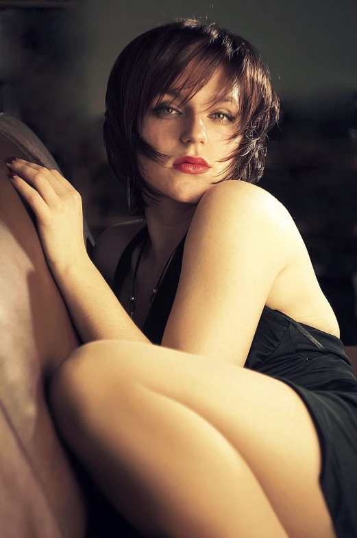 a woman in a black dress sitting on a couch, by Thomas Bock, flickr, photorealism, brown short hair, sexy lips :5 stylish, rachel mcadams, glamorous jill valentine