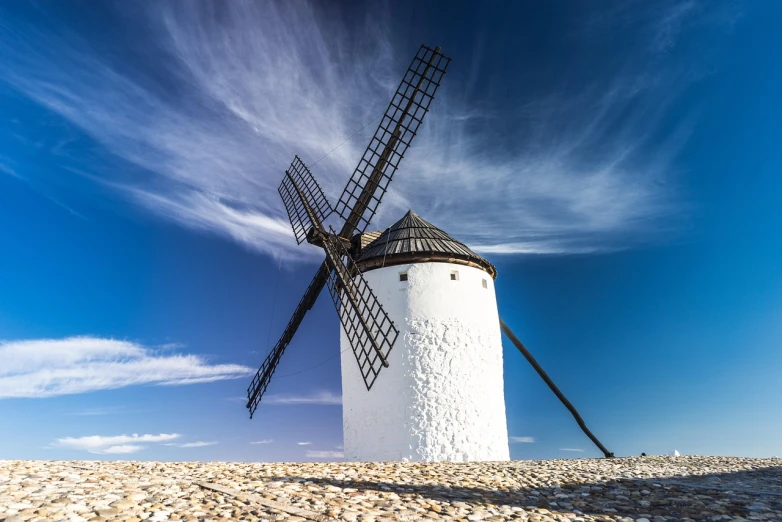 a windmill sitting on top of a sandy beach, a picture, by Juan Giménez, shutterstock, baroque, with a long white, wide angle photo, tourist photo, mill