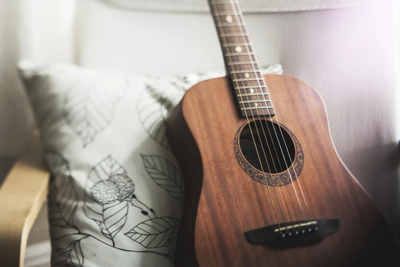 a guitar sitting on top of a pillow next to a lamp, a picture, by Romain brook, pixabay, detailed natural lighting, a wooden, mobile wallpaper, ✨🕌🌙