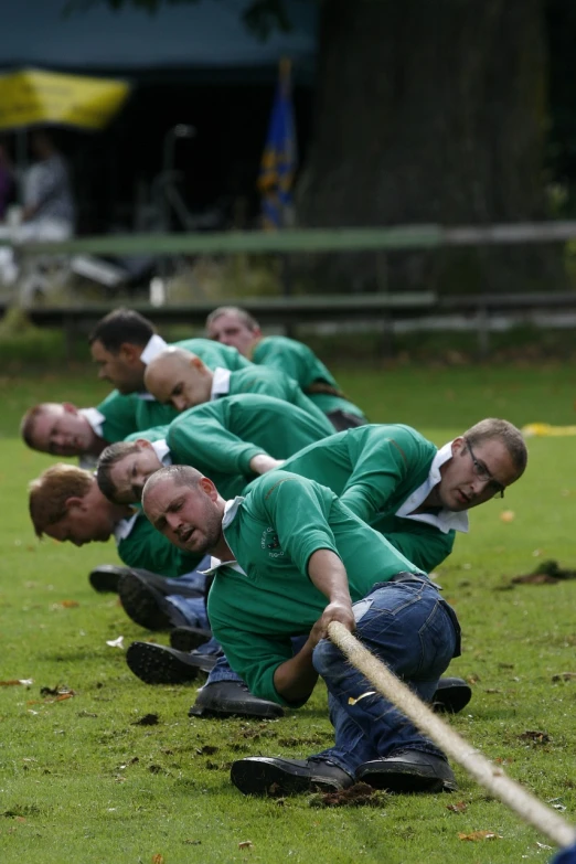 a group of men in green shirts pulling a rope, by Dietmar Damerau, flickr, crawling on the ground, longbows, esher, photograph credit: ap