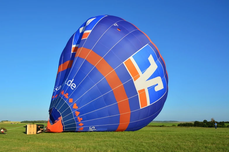 a large blue and orange hot air balloon in a field, a picture, by Jan Pynas, flickr, figuration libre, half turned around, yand.re, promotional photography, maintenance photo