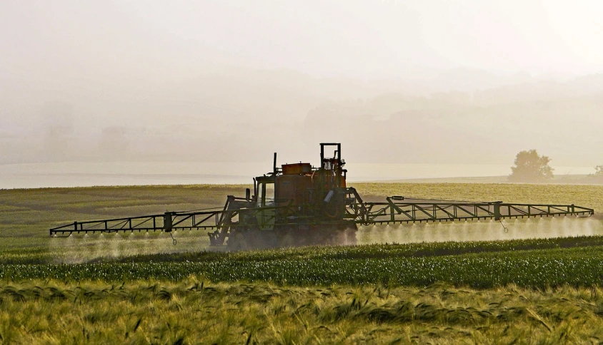 a tractor spraying a field with a sprayer, a picture, by David Simpson, precisionism, filtered evening light, oil dereks on horizon, bay area, istockphoto