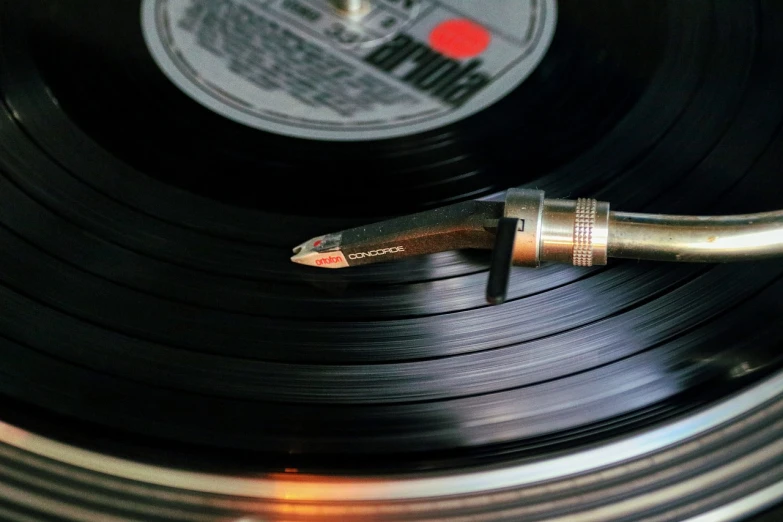 a record with a pencil sticking out of it, an album cover, by Jay Hambidge, pexels, smooth shiny metal, 1 9 7 0 s photo, turntablist, detailed product photo