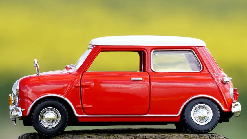 a red toy car sitting on top of a tree stump, trending on pixabay, photorealism, banner, mini cooper, on a bright day, 1959