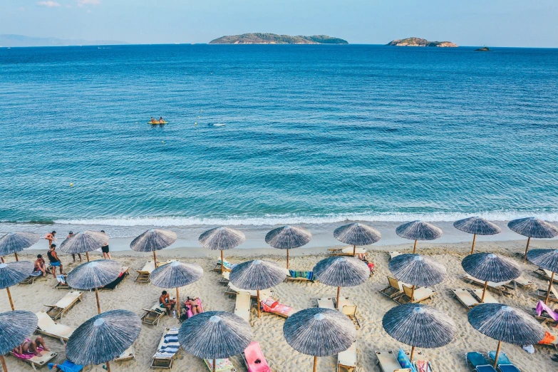 a beach filled with lots of umbrellas next to the ocean, by Alexander Fedosav, shutterstock, greece, usa-sep 20, news photo, miko