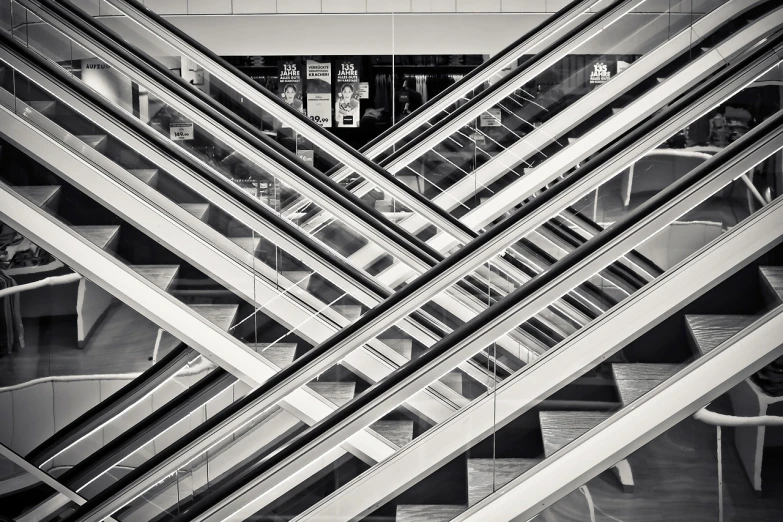 a black and white photo of an escalator, inspired by Andreas Gursky, precisionism, hyperdetailed samsung store, modern details, cross composition, beams