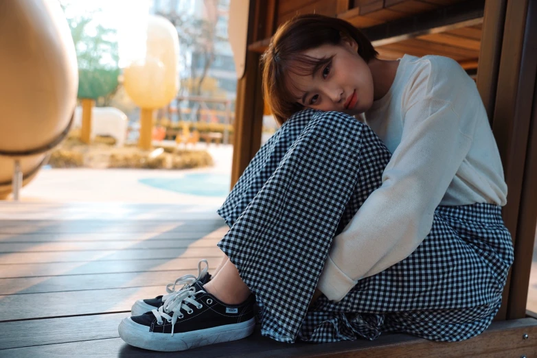 a woman sitting on top of a wooden bench, a picture, inspired by Ma Yuanyu, unsplash, shin hanga, on a checkered floor, sneaker photo, young cute wan asian face, realism style