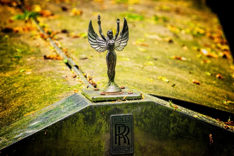a close up of a car hood ornament with a bird on it, an art deco sculpture, by Roger Cecil, pixabay contest winner, renaissance, goddess of death in a graveyard, scale model photography, wings spread, 2 4 mm iso 8 0 0 color