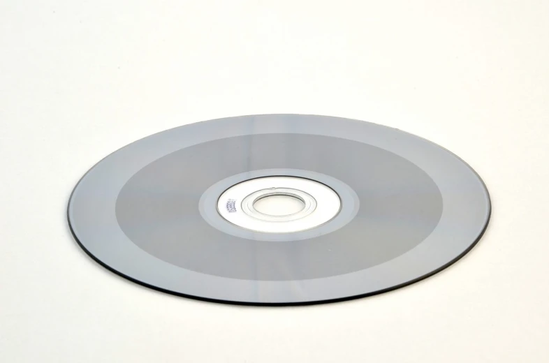 a close up of a disc on a white surface, 435456k film, grey and silver, dvd, thin porcelain