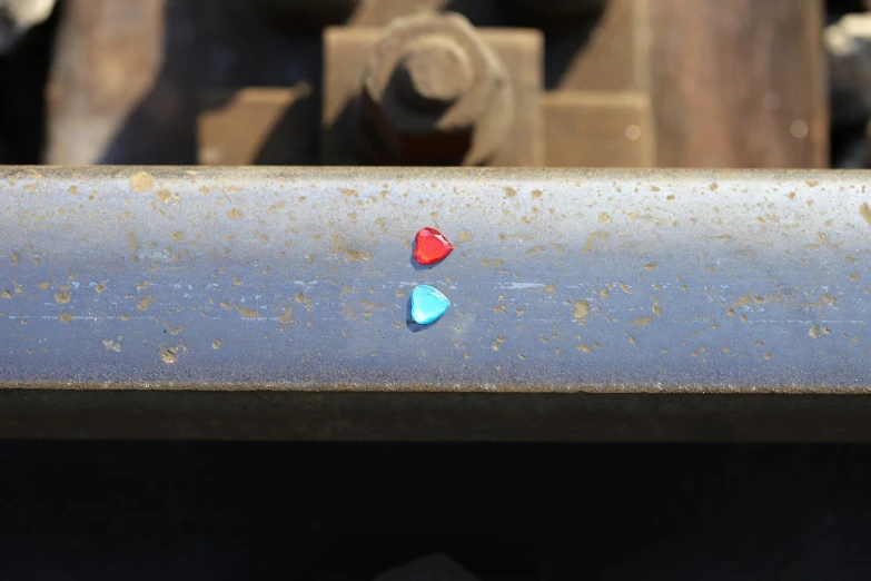 a red heart sitting on top of a metal pipe, a macro photograph, minimalism, colored gems, blue and red two - tone, railroad, triangular elements