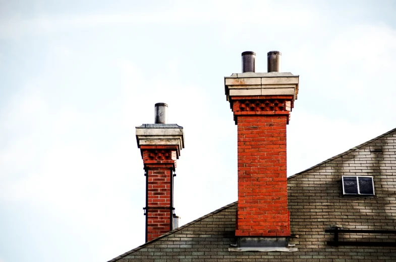 a couple of chimneys sitting on top of a roof, red bricks, traditional fireplace, low angle photo, modern photo
