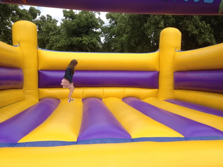 a little girl standing on top of an inflatable bouncer, a cartoon, by Edward Corbett, pexels, happening, yellow and purple color scheme, al fresco, bespoke, jump kick
