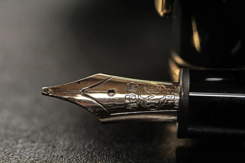 a fountain pen sitting on top of a table, a macro photograph, by Adam Szentpétery, pixabay, realism, jewelry engraved in scarab, close - up profile, shiny gold, dark shading