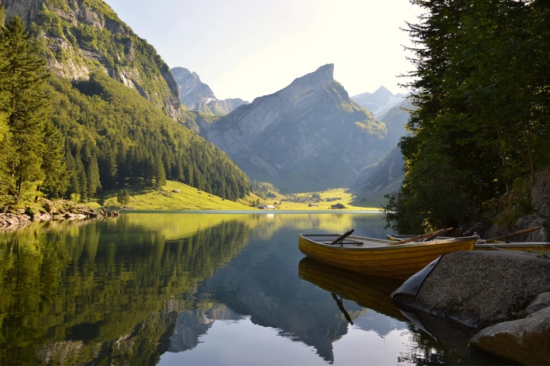 a boat sitting on top of a lake next to a forest, a picture, by Franz Hegi, lovely valley, sound of music, perfectly calm waters, spectacular mountains