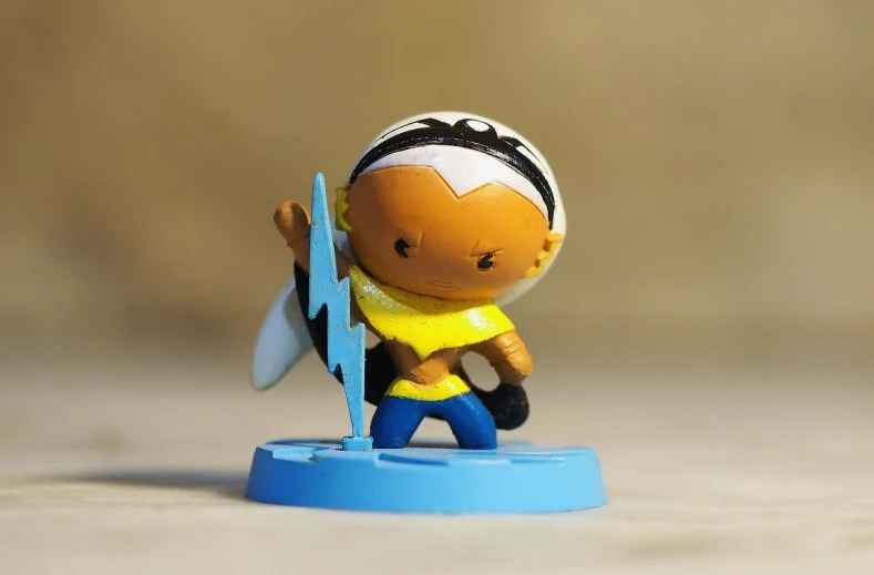 a close up of a toy figurine on a table, flickr, female lightning genasi, yellow and blue, mixed race, cartoon character