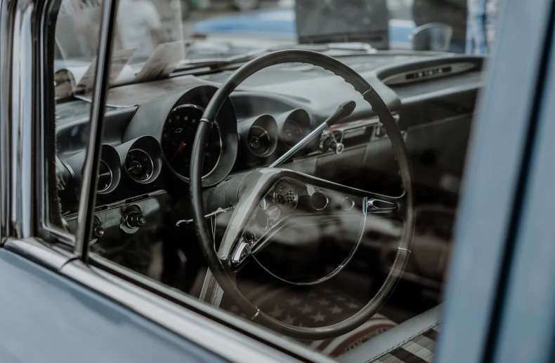 a close up of a steering wheel in a car, a portrait, by Matthias Weischer, pexels contest winner, photorealism, inside in a glass box, nostalgic atmosphere, shades of blue and grey, stock photo