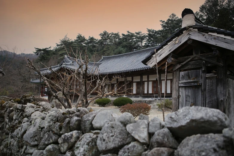 a stone wall with a building in the background, a tilt shift photo, inspired by Kim Hong-do, shin hanga, beautiful dusk, old asian village, january, very sharp and detailed photo