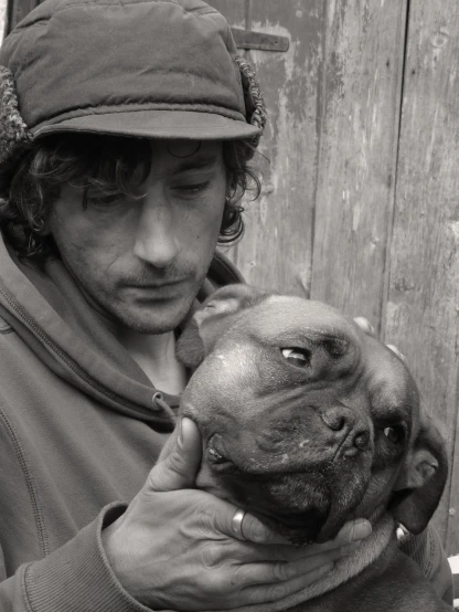 a black and white photo of a man holding a dog, a portrait, inspired by Roger Ballen, unsplash, renaissance, pug-faced, young simon baker, environmental portrait, coloured