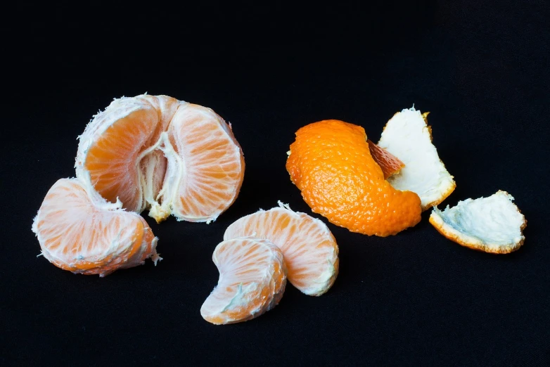 a peeled orange sitting on top of a black surface, a still life, various posed, iso 4 0 0, citrinitas, hyperdetailled