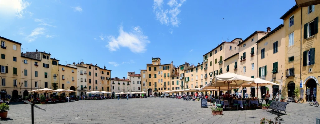 a group of people sitting under umbrellas in a courtyard, by Carlo Martini, shutterstock, renaissance, panoramic widescreen view, town square, bizzaro, blue sky