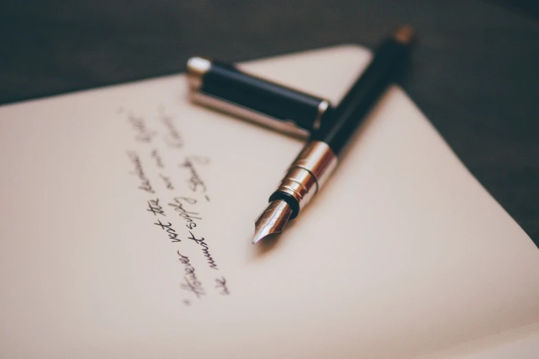 a pen sitting on top of a piece of paper, by Niko Henrichon, unsplash, elegant scene, letters, well drawn, dignifying