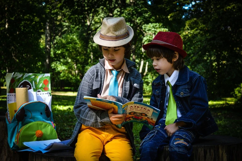 two children sitting on a bench reading a book, a portrait, by Maksimilijan Vanka, pixabay, caracter with brown hat, costume, [ colourful, political meeting in the woods