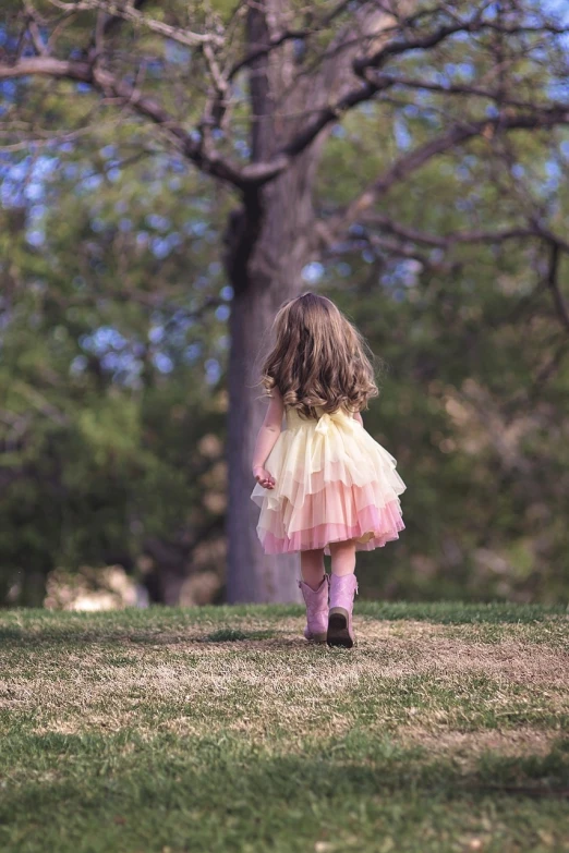 a little girl that is walking in the grass, a picture, inspired by Kate Greenaway, pexels, knee-high boots, pink and yellow, back - shot, soft muted colors