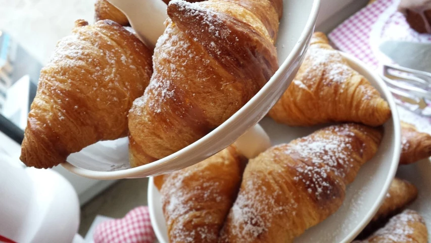 a tray of croissants sitting on top of a table, by Tom Wänerstrand, glittering and soft, closeup - view, breakfast buffet, diagonal