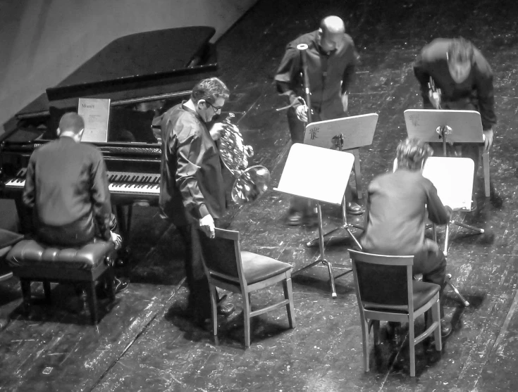 a group of people sitting around a piano, by Ejnar Nielsen, flickr, on an empty stage from above, gloves and jewelry. motion, jaroslaw jasnikowski, orchestra