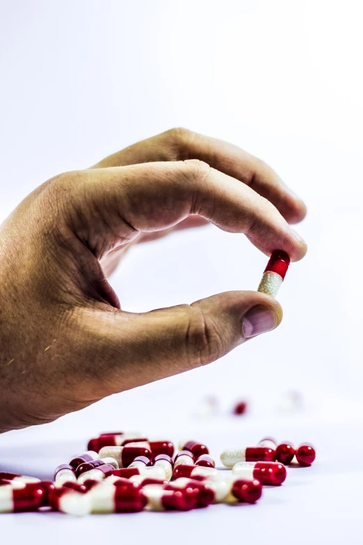 a person taking a pill out of a pile of red and white pills, minimalism, sharp photo, very sharp photo, tubes fused with the body, portlet photo