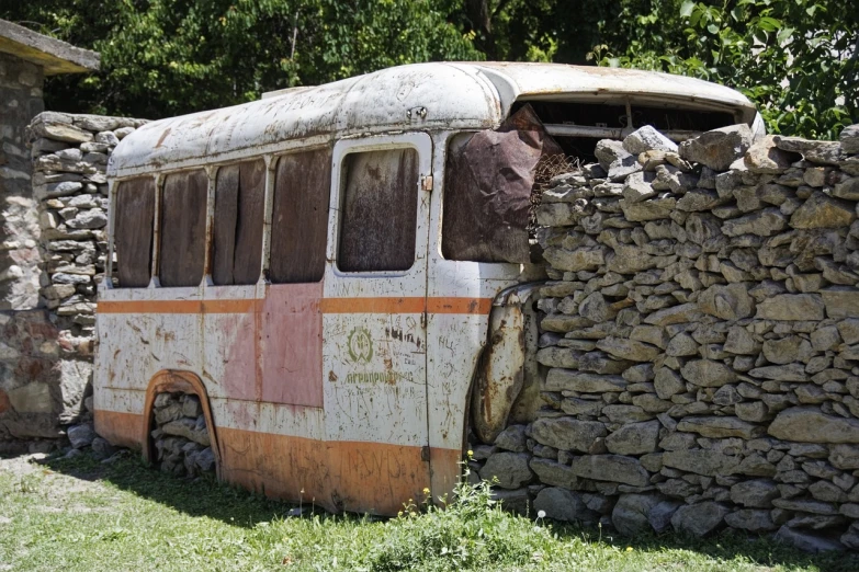 an old bus parked next to a stone wall, flickr, georgic, a ancient crashed spaceship, nepal, complex details