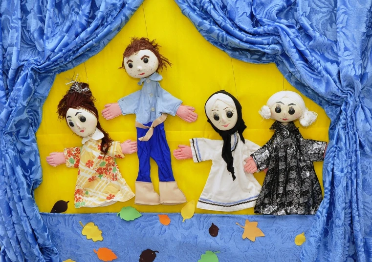 a group of dolls sitting on top of a blue curtain, a picture, folk art, four hands, in autumn, children's tv show, square